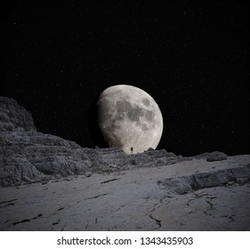 Lone walker silhouetted against the Moon in the mountains at night.