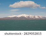 A lone white cloud drifting above vast snow‑dusted Patagonian peaks and turquoise waters (Calafate, Argentina: 12-sep-2011)