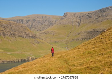 A lone woman hiking along the fjords of Vagar in the Faroe Islands. - Powered by Shutterstock