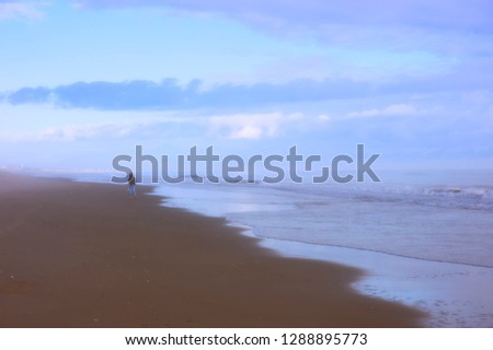lone woman walking along the beach on the atlantic ocean