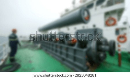 A lone worker stands on the deck of a large industrial ship, overseeing heavy machinery and equipment.