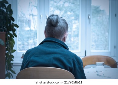 Loneliness concept, old-age depression: lonely old woman looking out of the window, blue filter effect. - Powered by Shutterstock