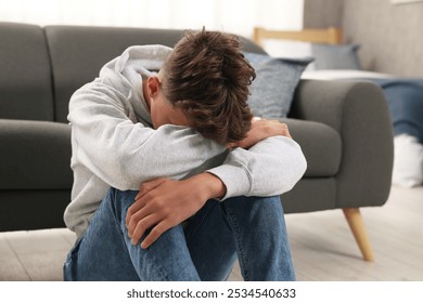 Loneliness concept. Sad teenage boy on floor at home - Powered by Shutterstock