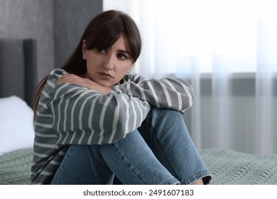 Loneliness concept. Sad woman sitting on bed at home - Powered by Shutterstock