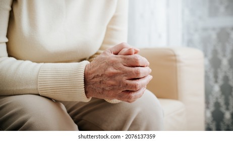 Loneliness of elderly, sadness, depression, mental female health concept. Close-up of senior mature woman's wrinkled hands folded on her feet indoors. Side view. - Powered by Shutterstock