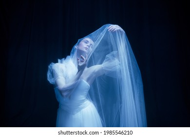 Loneliness. Young Graceful Beautiful Woman, Balerina In White Wedding Dress In Art Performance Isolated On Dark Background In Neon Light. Concept Of Love, Relationship, Beauty, Art And Theater.