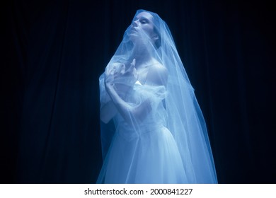 Loneliness. Young Graceful Beautiful Woman, Balerina In White Wedding Dress In Art Performance Isolated On Dark Background In Neon Light. Concept Of Love, Relationship, Beauty, Art And Theater.