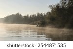 lonely angler fishing in the morning over foggy waters