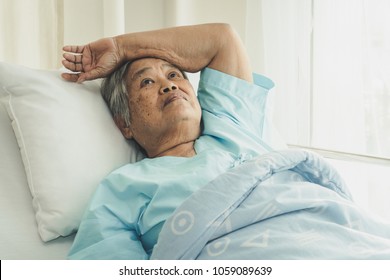 Lonely Asian Elderly Female Patient Lying On The Bed In The Hospital And Looking Away Outside The Window Waiting To See Her Child And Her Family To Visit.