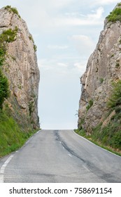 Lonely Asphalt Country Road Diminishing To The Vanishing Point In The Horizon And Crossing A Mountain Gorge. It Evoques Travel Uncertainty, But The Steep Walls Also Talk Of No Choice And Determinism.