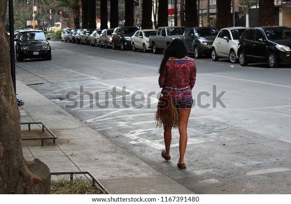 Lonely beautiful woman walking on the street of\
metropolis, latina woman in mexico city, city street with cars and\
lonely woman, Mexico\
city