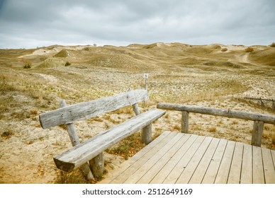 Lonely bench in the sandy Dead Dunes of Curonian Spit, Lithuania, marked by minimal vegetation and covered by a layer of clouds. UNESCO World Heritage. - Powered by Shutterstock