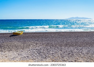 Lonely boat at Avis beach,Anafi island in the distance. located close to the southern end of the Santorini International airport.Picture taken in Kamari ,Santorini,Greece- unique,amazing Aegean island - Shutterstock ID 2303725363