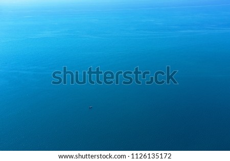 Lonely boat in the vast blue sea surface