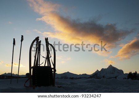 lonely bobsleigh standing in front of sunset landscape with mountains  and glowing clouds