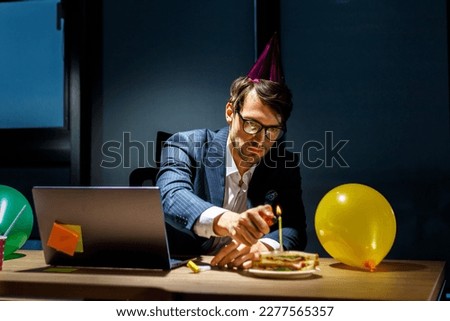 lonely boss in the office in the evening celebrates a birthday alone. Office party, corporate event or holiday