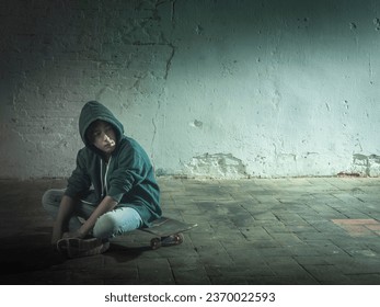 Lonely boy sitting on his skateboard. Cold and lonely environment. - Powered by Shutterstock