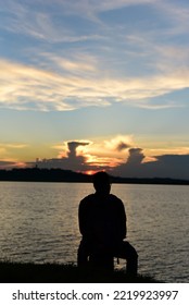 Lonely Boy Sitting On The Rock At Sunset.