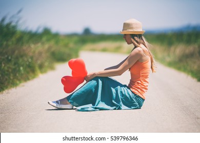 Lonely broken hearted woman is sitting on country road, intentionally toned.