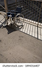 Lonely Broken Wheel Chair Standing In The Sun. 