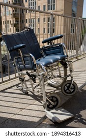 Lonely Broken Wheel Chair Standing In The Sun. 