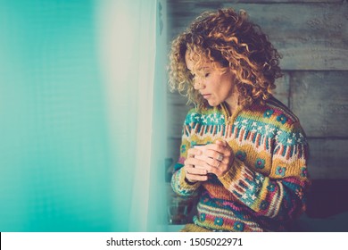 Lonely cacuasian adult lady at home - people relaxing and taking his own time lost in own thoughts - portrait of beautiful middle age woman with cup of coffee