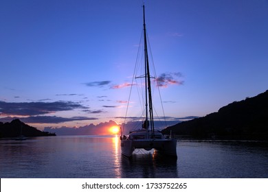 Lonely Catamaran In A Quiet Lagoon Near The Island Of Bora Bora At Sunset In French Polynesia