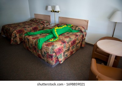 Lonely Dinosaur Man Lying Face Down On The Bed In A Dark Motel Room