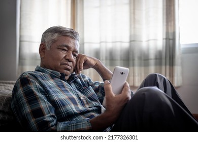 Lonely Elderly Man Sitting Alone On Bedroom And Looking At Phone