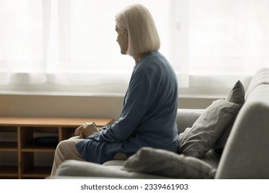 Lonely elderly retired woman sitting on sofa at home, feeling lost, depressed, stressed, apathy, going through health problems, loss, grief, suffering from memory loss, thinking on problems - Powered by Shutterstock