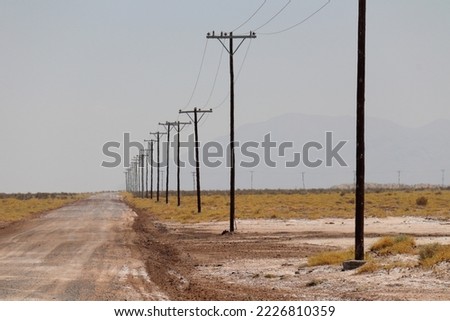Lonely empty gravel road with poles stretching for miles into the desert