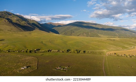 Lonely Farm At The Foot Of The Mountain. Mountain Landscape At Sunset In Summer. Photos Of The Republic Of Gorny Altai In Summer, Aerial Photography, Russia