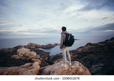 Lonely figure or adventurer and explorer with big backpack for drone, stand on top of mountain or cliff on sunset. Looks out for perfect shot perspective, travel inspiration destination - Powered by Shutterstock