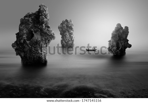 Lonely Fisherman On Stone Beach Black Stockfoto (redigera