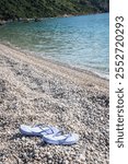 Lonely footwear on Jaz Beach which is one of the longest in the Budva, Montenegro area. The beach is known for its stunning turquoise waters and surrounding rocky cliffs. 