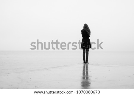 A lonely girl looks out into the distance in the rain. Black and white. Loneliness