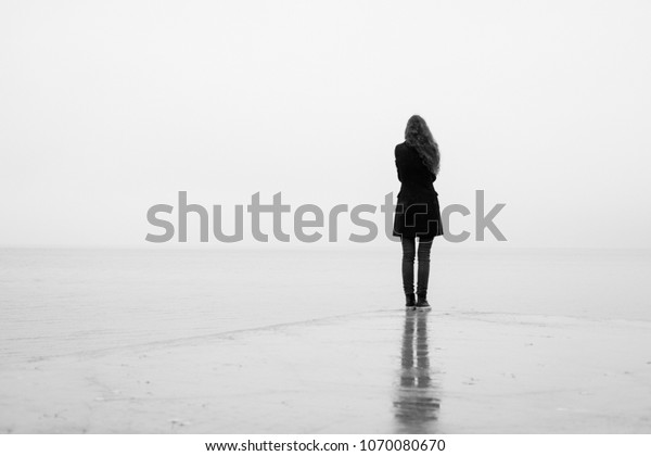 A lonely girl looks out into the distance in the rain. Black and white. Loneliness