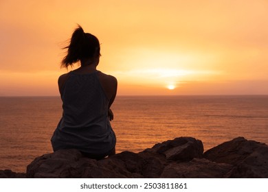 Lonely girl observes the sunset over the sea.Concept of solitude or reflection - Powered by Shutterstock