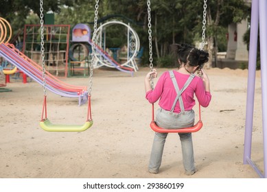 Lonely girl sitting on chain swing in the park - Powered by Shutterstock