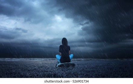 a lonely girl sitting on a wood in a rainy weather. 