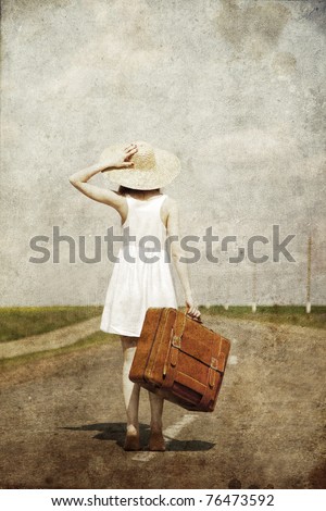 Lonely girl with suitcase at country road.. Photo in old image style.