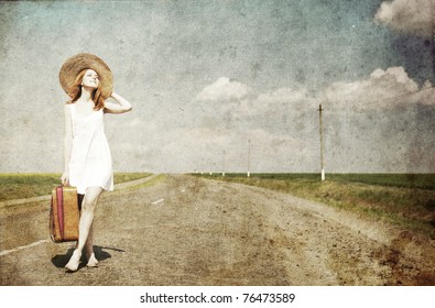 Lonely girl with suitcase at country road.Photo in old image style.