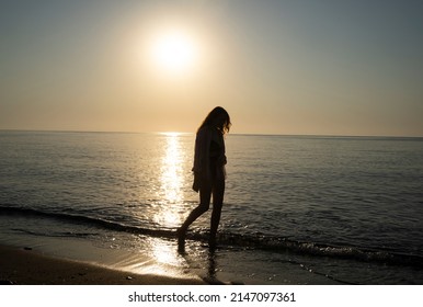 Lonely Girl Walking Along The Beach At Dawn