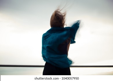 lonely girl's silhouette against sky, wind playing with hair and scarf flying up