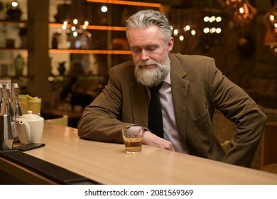 Lonely Gray-haired Man Drinking Whiskey At A Bar