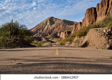 Lonely Highway With Yellow Middle Line In A Beautiful And Arid Desert Landscape Showing Cactus And Desert Rock Formations, Peru, South America