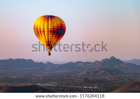 A lonely hot air balloon flies over Phoenix Arizona with the Sonoran Desert in the background.