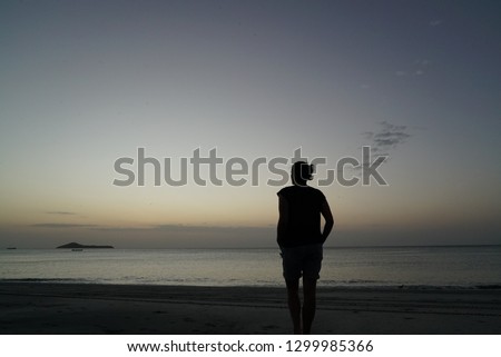 Lonely human silhuette on the sea cost looking at sunset above a water. Solitary, silence and reclusion concept