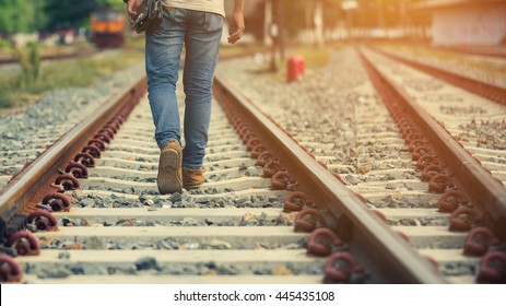 Lonely journey.Man walking on rail road with warm sunlight. - Powered by Shutterstock