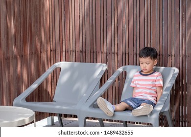 Lonely kid boy sitting alone. Lonely kid with bored face. Preschool child with unhappy or sad face. Copy space for text. 